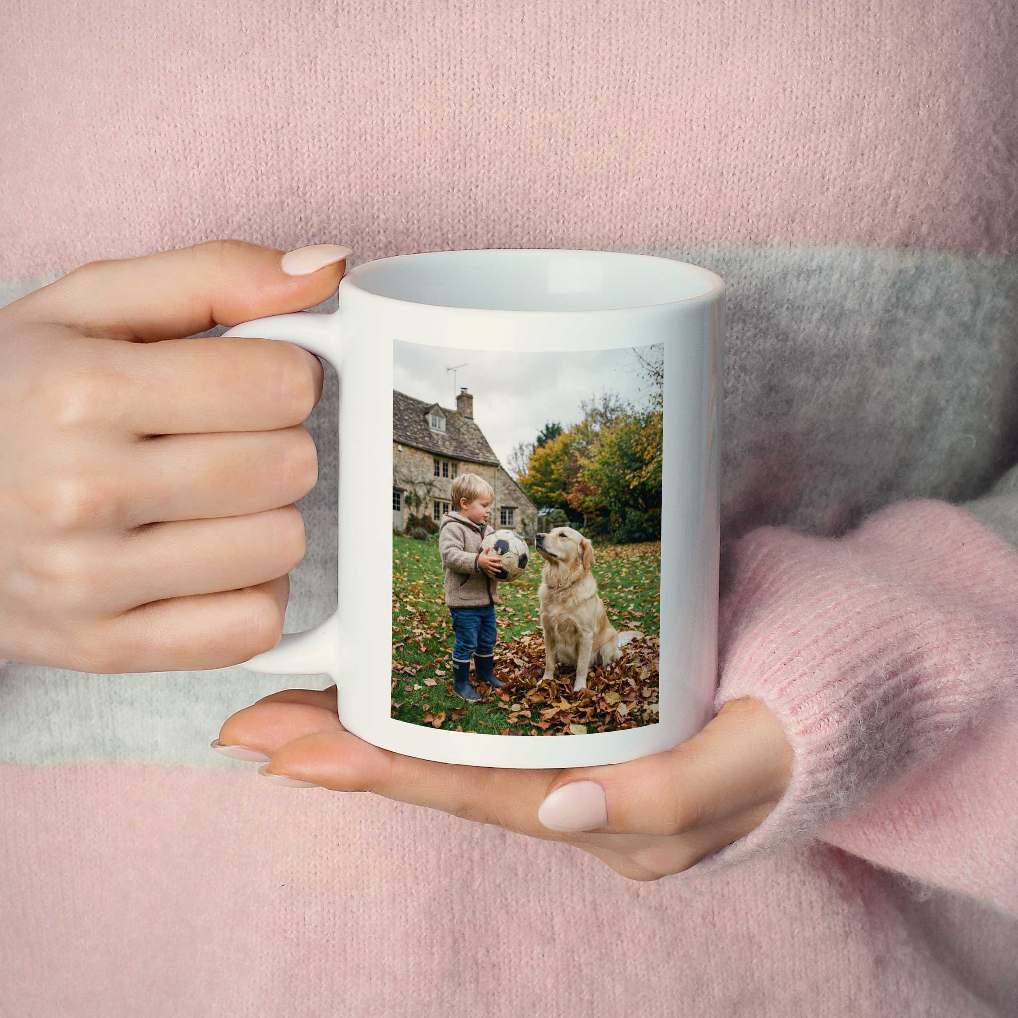 Junge Frau hält eine Grosse Nova Fotoasse mit dem Erinnerungsfoto ihres Kindes beim spielen mit dem Hund.