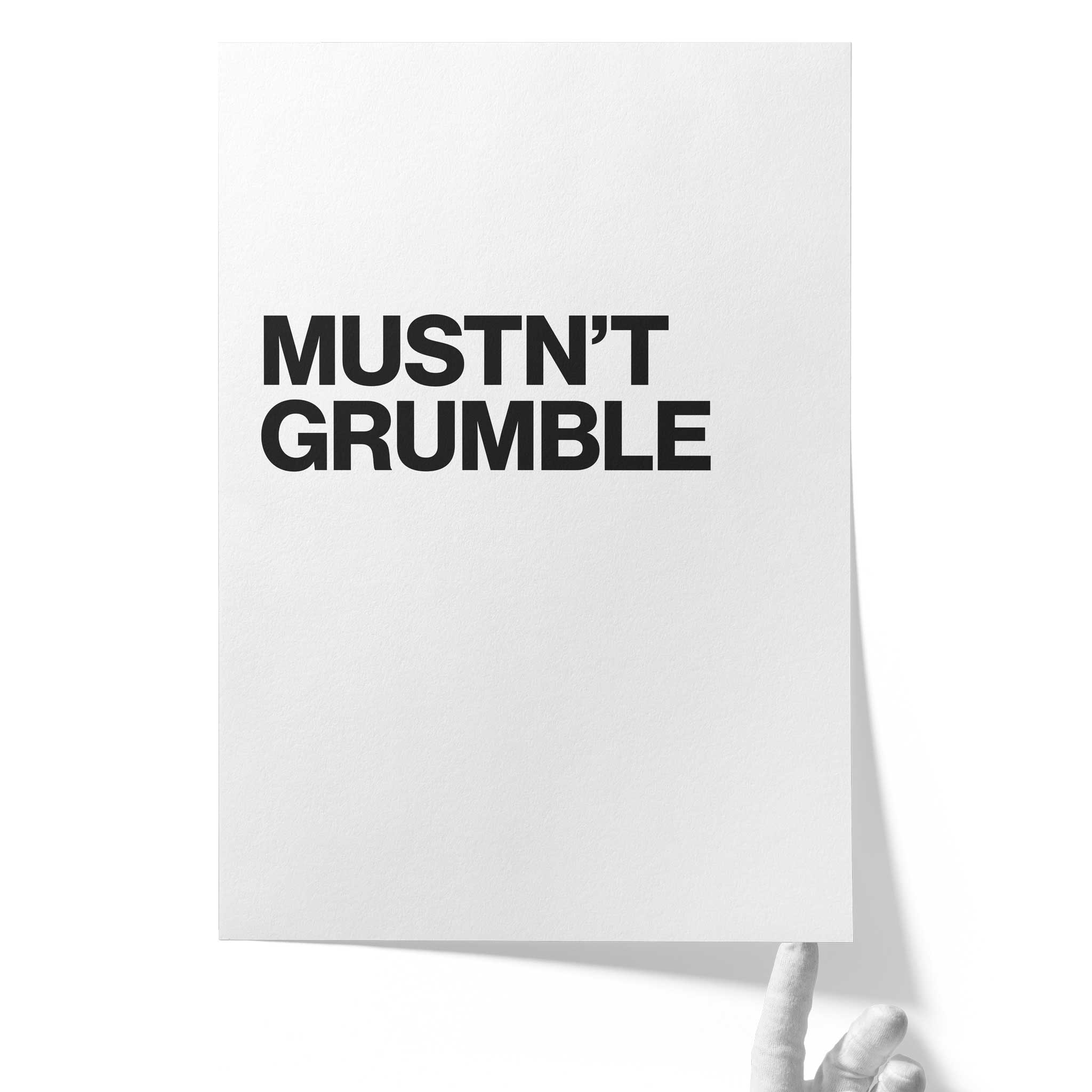 Weißes Fine‑Art‑Papier auf Hahnemühle Photo Rag 308, unten von einer Hand gehalten, bedruckt mit dem typografischen Satz „MUSTN’T GRUMBLE.“ in fetter schwarzer Schrift.