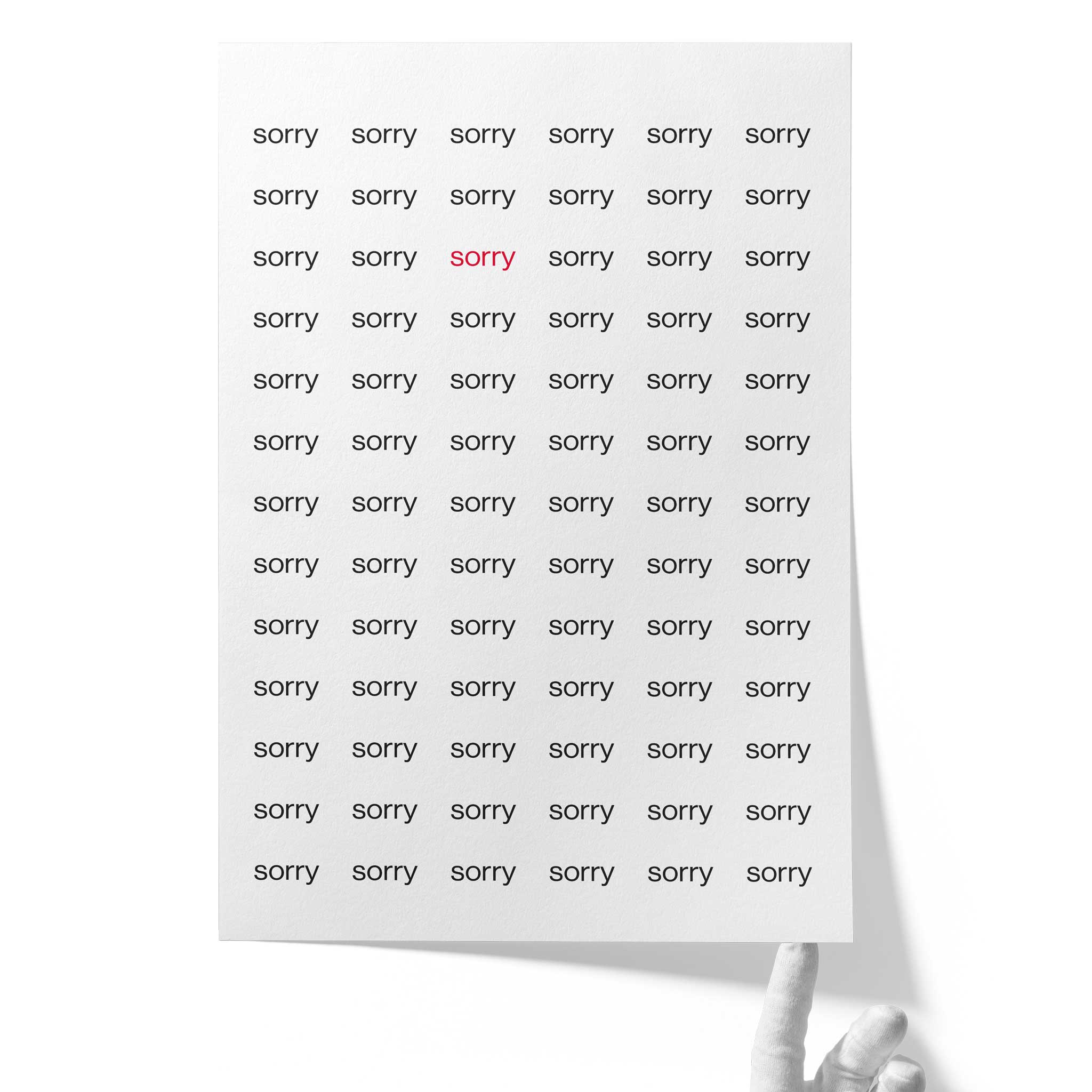 Weißes Fine‑Art‑Papier auf Hahnemühle Photo Rag 308, unten von einer Hand gehalten; ein regelmäßiges Raster aus dem Wort „sorry“ in Schwarz, mit einem einzelnen roten „sorry“ im Zentrum.